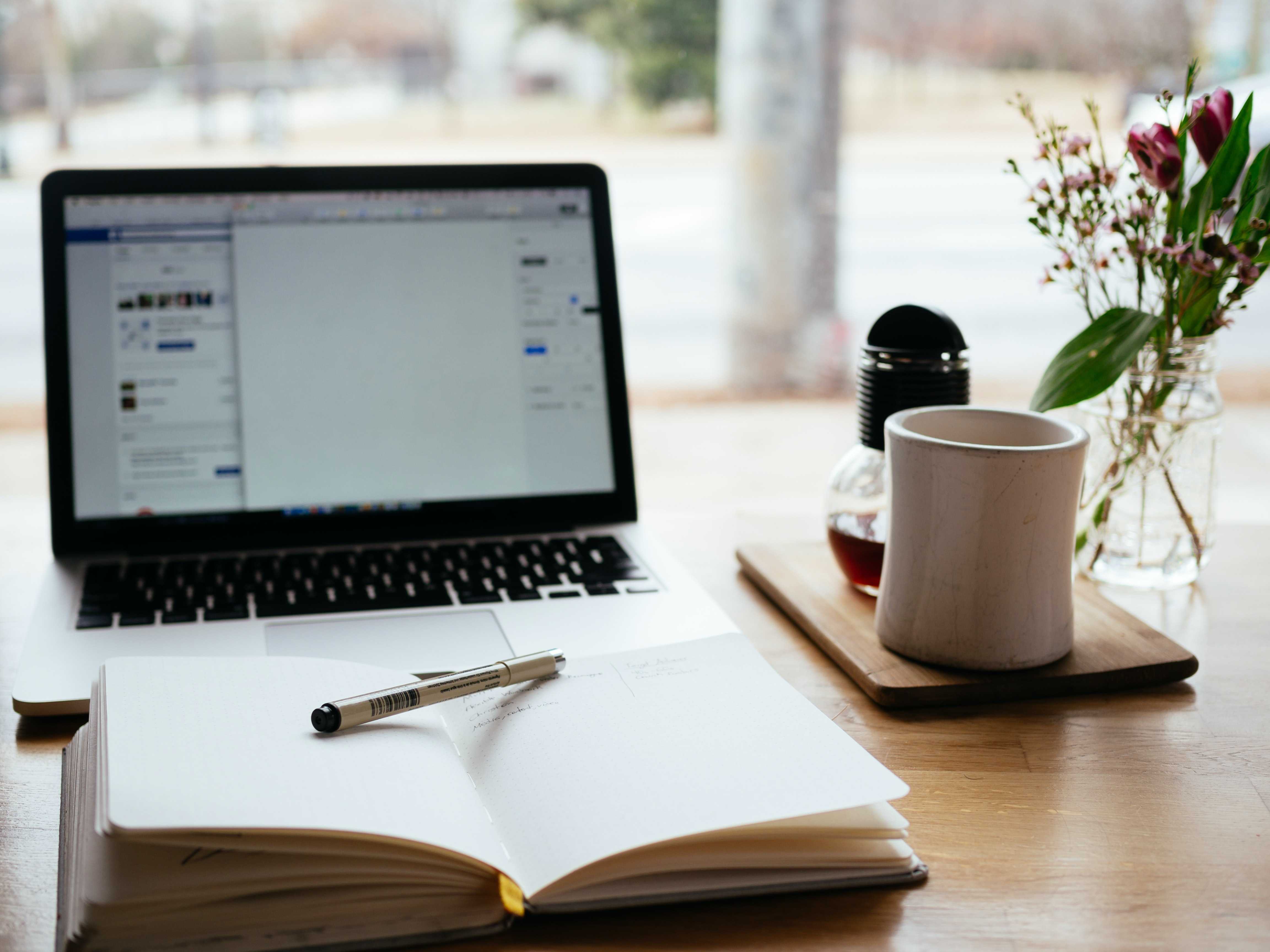 Laptop, notebook, pen and mug on a table