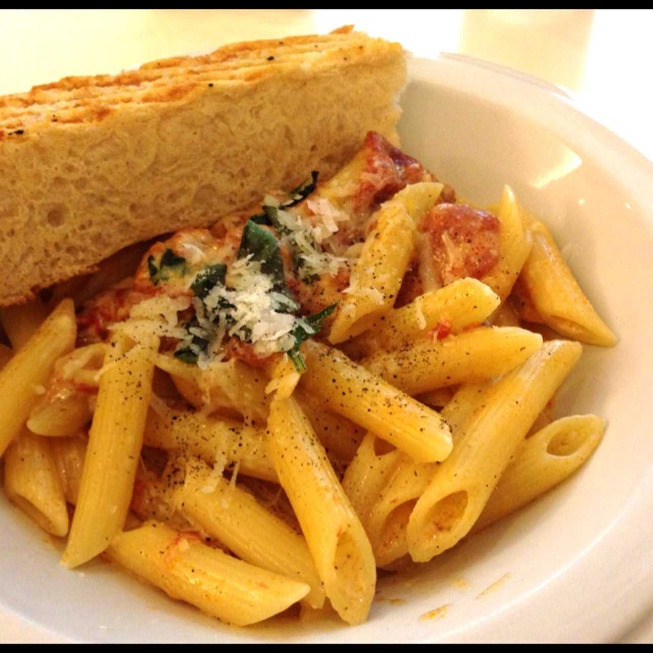 Penne pasta with basil and cheese and a slice of bread